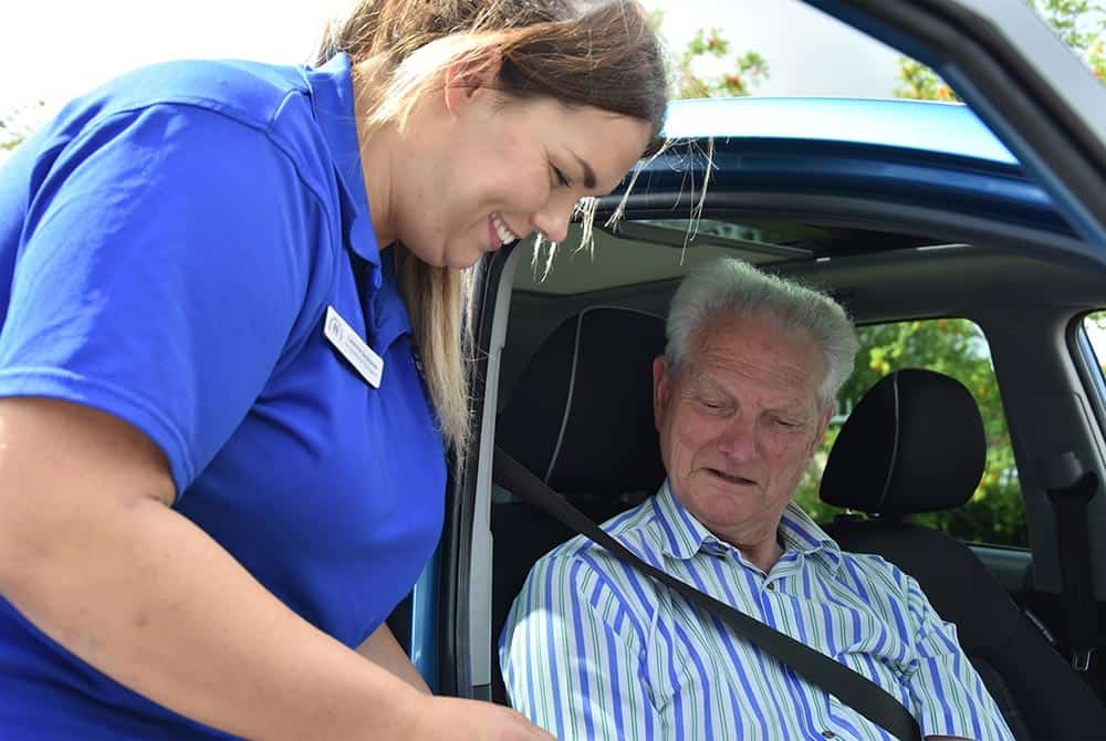 Woman assisting elderly man in car