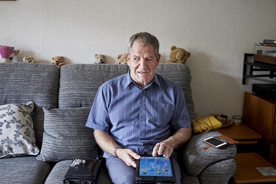 Visually impaired man using a tablet device at home image
